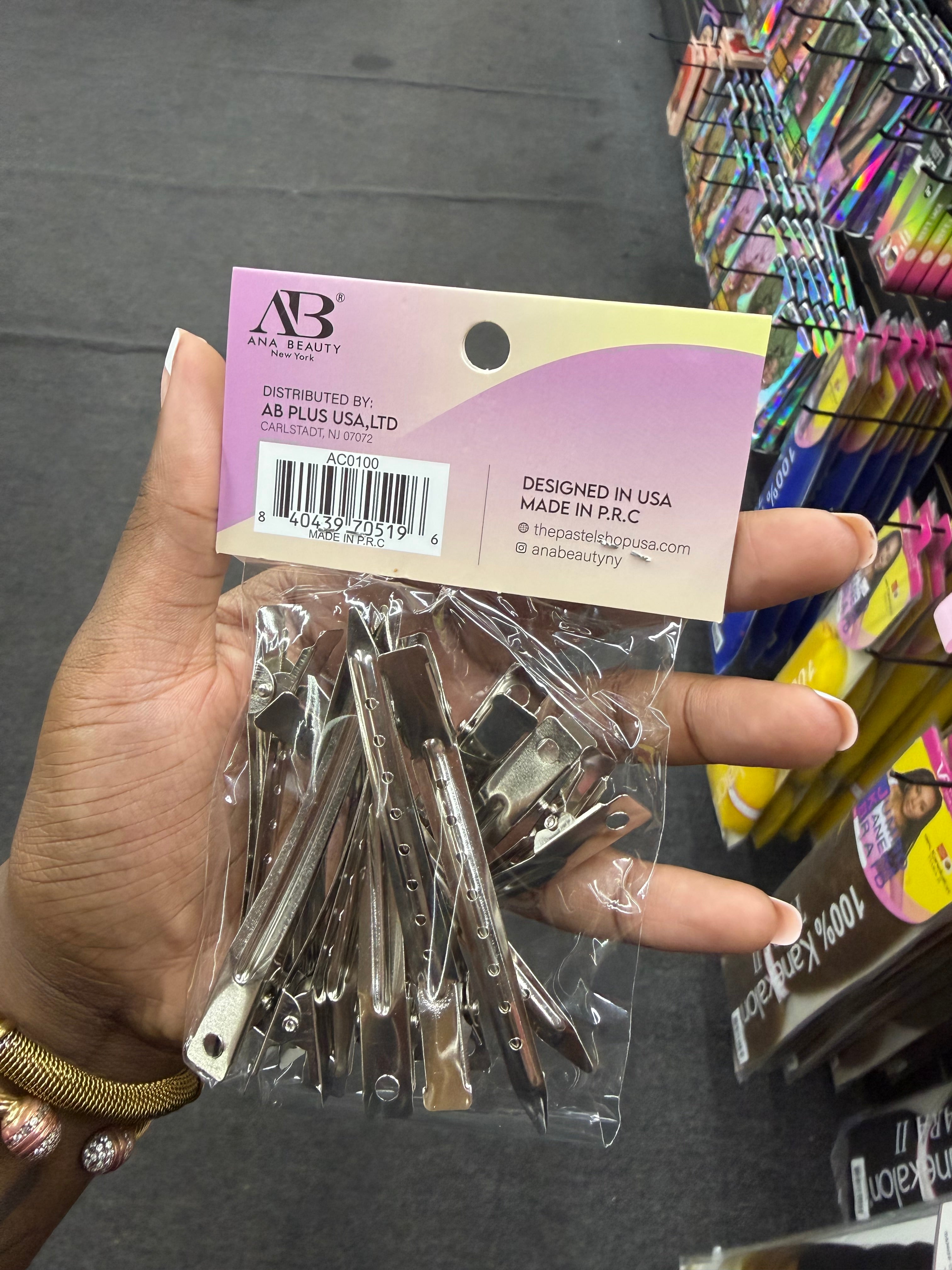 A hand holding a clear plastic bag of AB Plus USA nail clips with a branded paper header card, photographed in a retail store aisle.