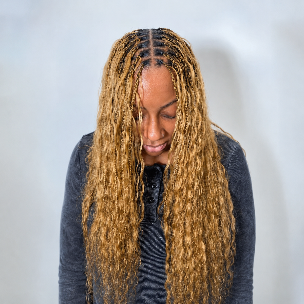Woman wearing honey blonde #27 Wet & Wavy human hair in long boho braids