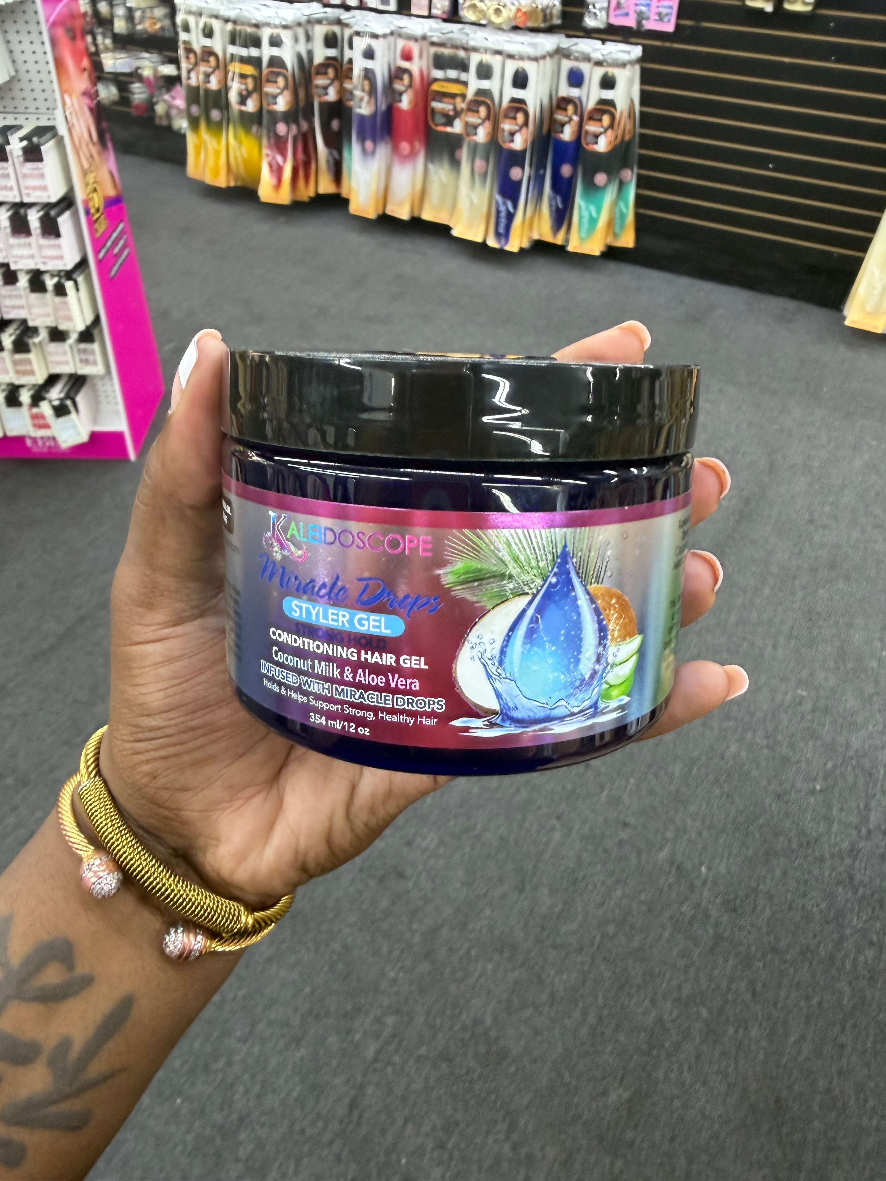A hand holding a jar of Kaleidoscope Brand Miracle Drops Styler Gel conditioner hair gel in a retail store setting.