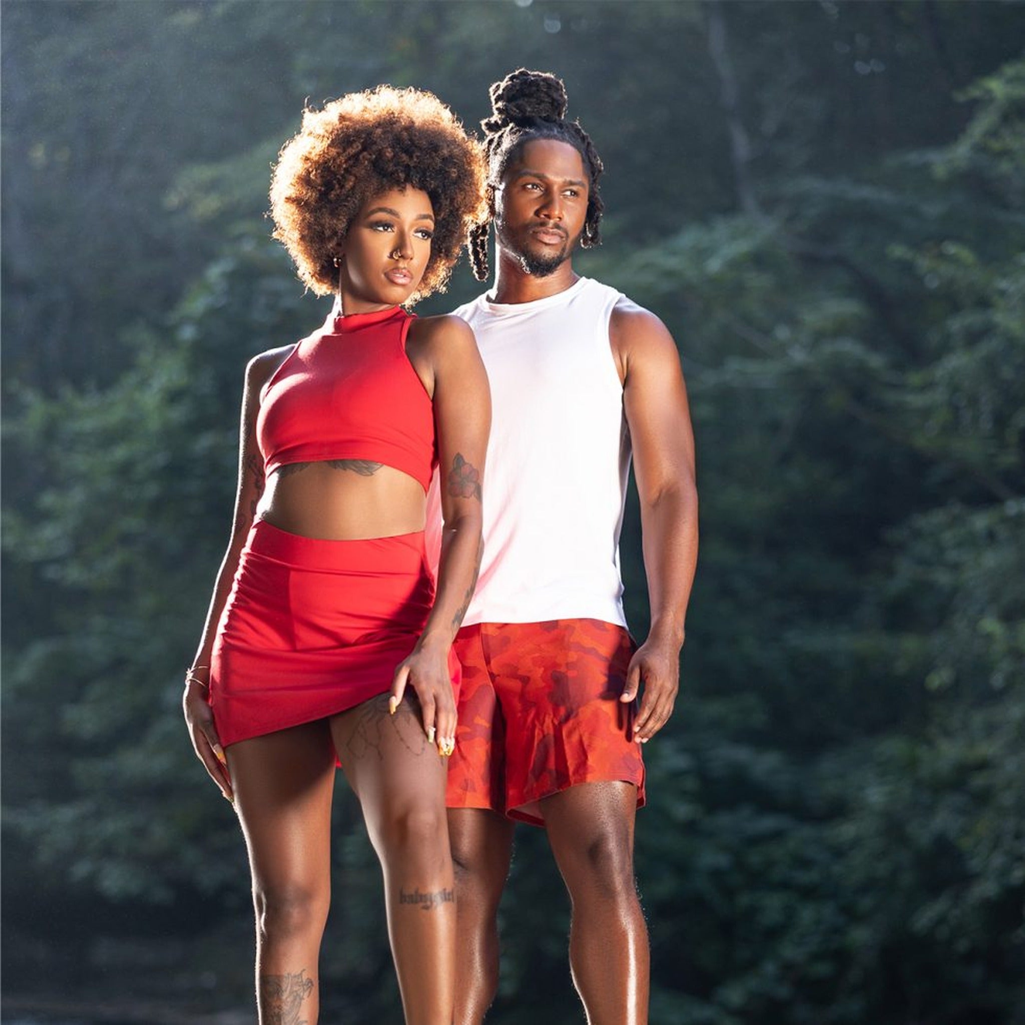 Two people in red athletic wear standing in a forest setting